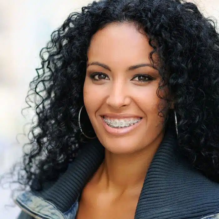 Smiling woman with curly hair wearing braces, representing orthodontic care in Highland Park, CA.