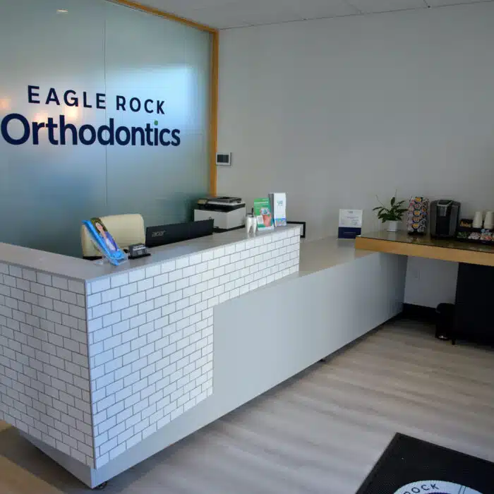 Eagle Rock Orthodontics reception area with a modern design, featuring a front desk, promotional materials, and a coffee station, emphasizing a welcoming environment for new patients.