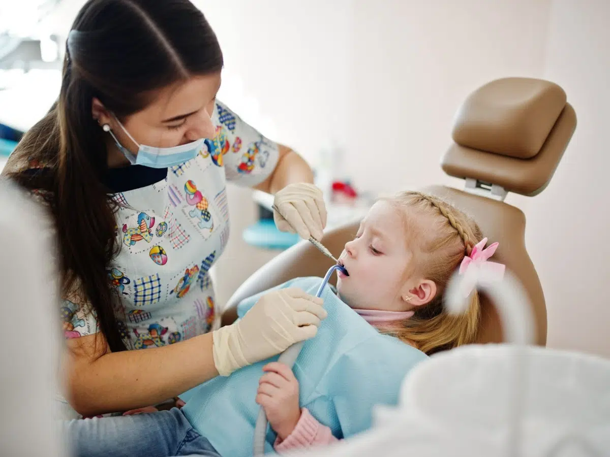 Child receiving dental care from orthodontist in a colorful clinic, emphasizing early orthodontic evaluations for healthy dental development.