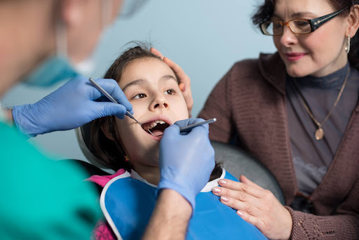 Orthodontist examining a child during an early orthodontic checkup for kids with a parent present